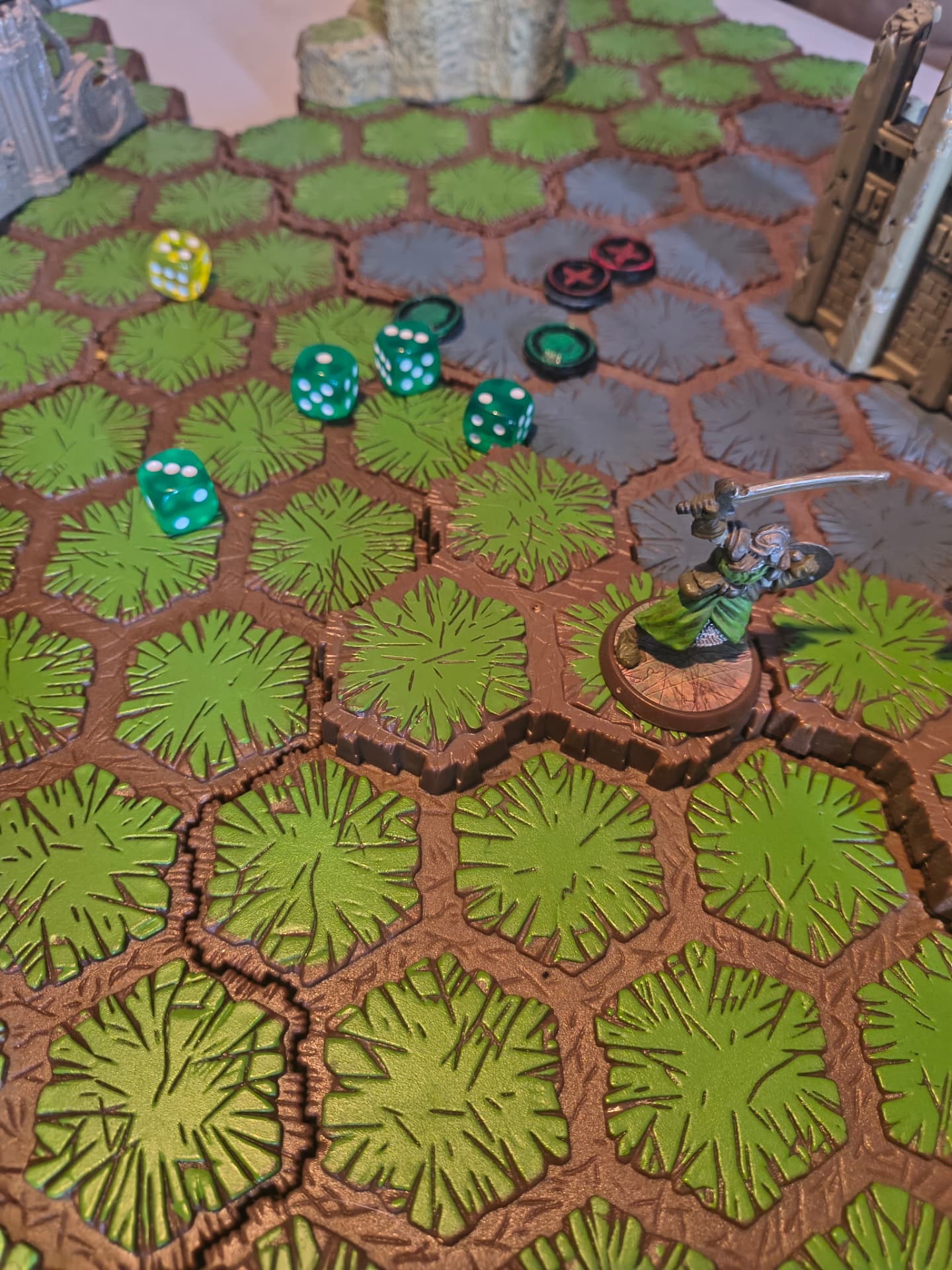 Hex tile battlefield with dice, tokens and a painted swordsman miniature